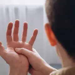 Osoba masuje dłoń, odczuwając drętwienie rąk w nocy.