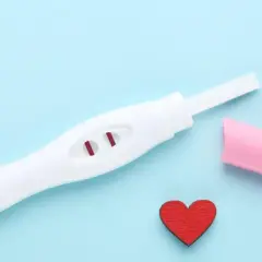 Pozytywny test ciążowy z dwoma czerwonymi kreskami. Kiedy zrobić test ciążowy? Serce symbolizuje miłość i nadzieję.