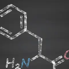 Struktura chemiczna fenyloalaniny, narysowana kredą na tablicy.