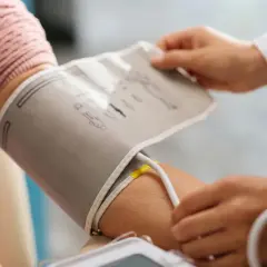 Lekarz zakłada mankiet ciśnieniomierza na ramię pacjenta. To ważny element monitorowania ciśnienia krwi, a ciśnienie krwi tabela wiekowa pomaga ocenić wyniki.