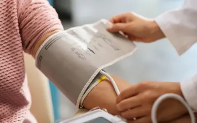 Lekarz zakłada mankiet ciśnieniomierza na ramię pacjenta. To ważny element monitorowania ciśnienia krwi, a ciśnienie krwi tabela wiekowa pomaga ocenić wyniki.