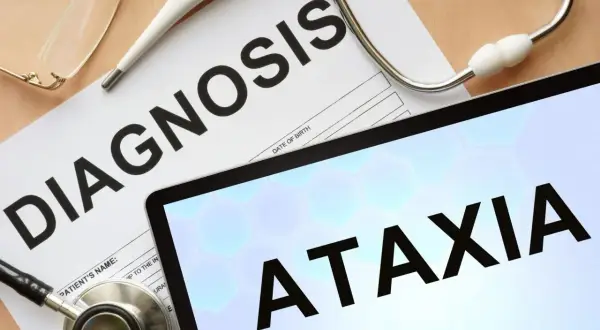 Stetoskop, termometr i okulary na papierze z napisem "DIAGNOSIS". Na ekranie tabletu widnieje słowo "ATAXIA", sugerujące diagnozę.