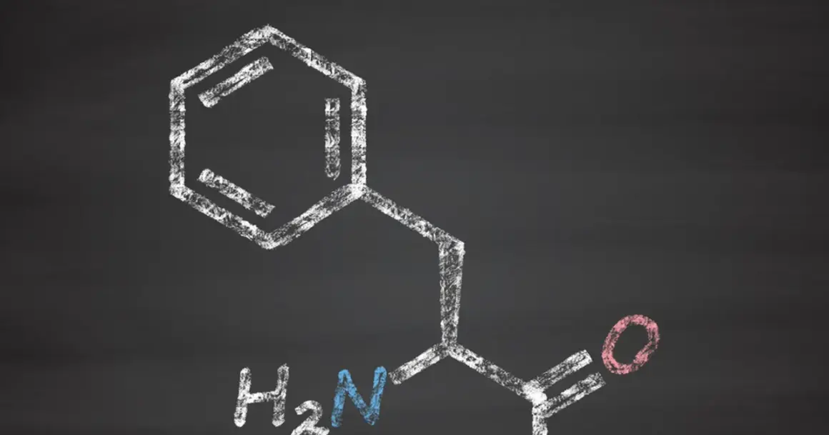 Struktura chemiczna fenyloalaniny, narysowana kredą na tablicy.