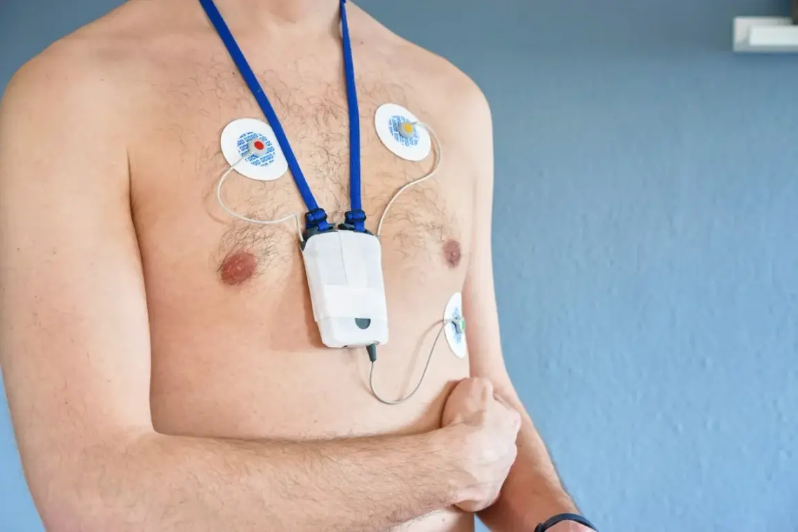 Mężczyzna z przyklejonymi elektrodami i urządzeniem holter ekg na klatce piersiowej, monitorującym pracę serca.