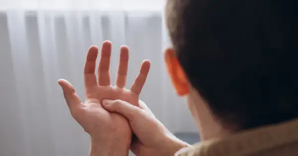Osoba masuje dłoń, odczuwając drętwienie rąk w nocy.