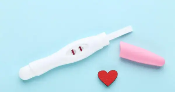 Pozytywny test ciążowy z dwoma czerwonymi kreskami. Kiedy zrobić test ciążowy? Serce symbolizuje miłość i nadzieję.